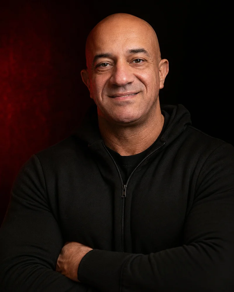 Akmal Kadri smiling in a professional black-and-red portrait.